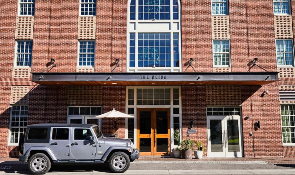 A close up of the entrance to the The Alida Savannah, A Tribute Portfolio Hotel, with a sliver jeep parked out front.