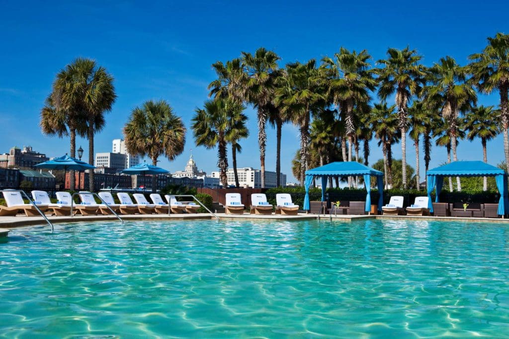 The outdoor pool at the The Westin Savannah Harbor Golf Resort & Spa, flanked by white loungers and blue cabanas on one side.