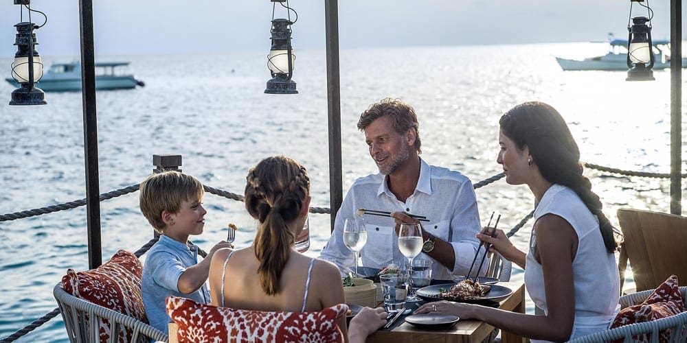 A family enjoyes dinner together at InterContinental Maldives Maamunagau Resort.