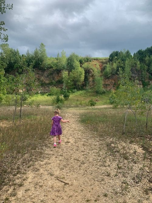 A young girl in a purple dress explores a trail while hiking near La Crosse, Wisconsin.