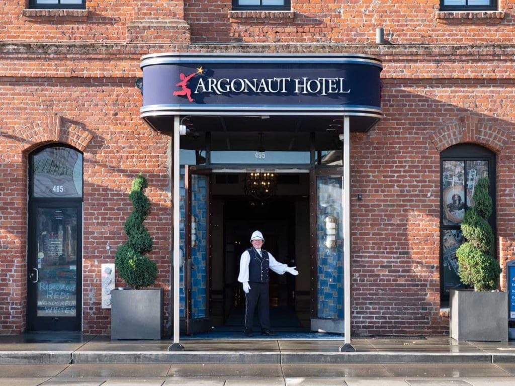A staff member stands welcoming guests to the entrance of the Argonaut Hotel - a Noble House Hotel.
