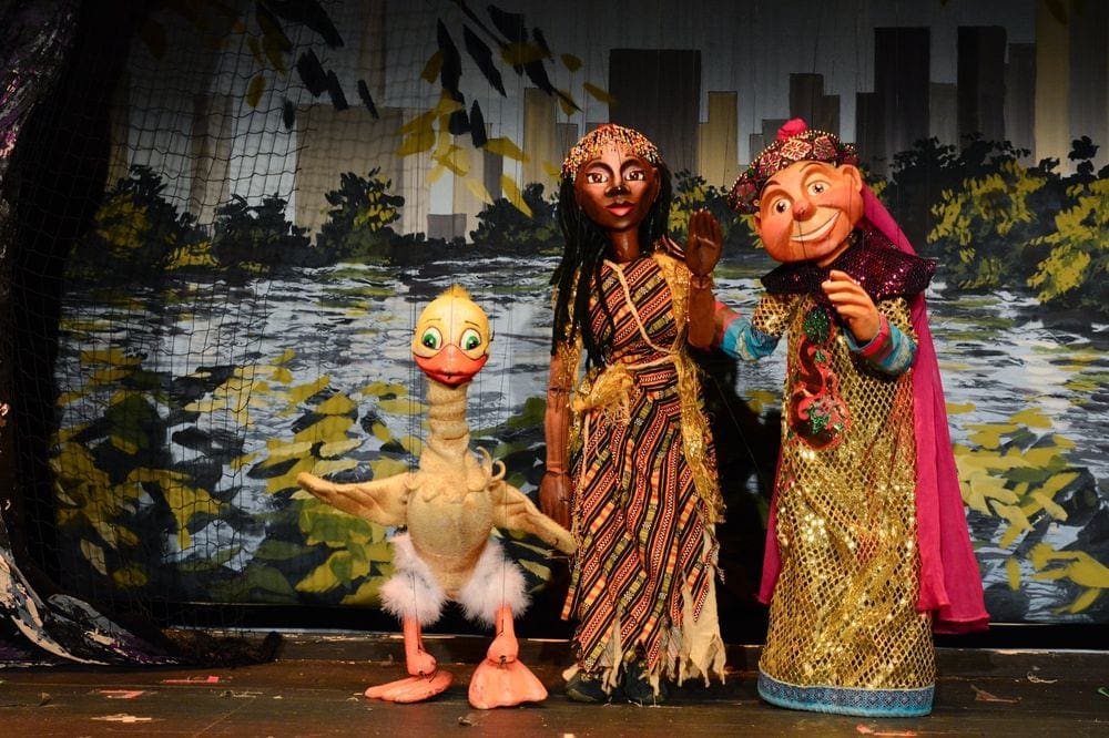 Three puppets, two people and one duck, on stage at a production for the Swedish Cottage Marionette Theater.