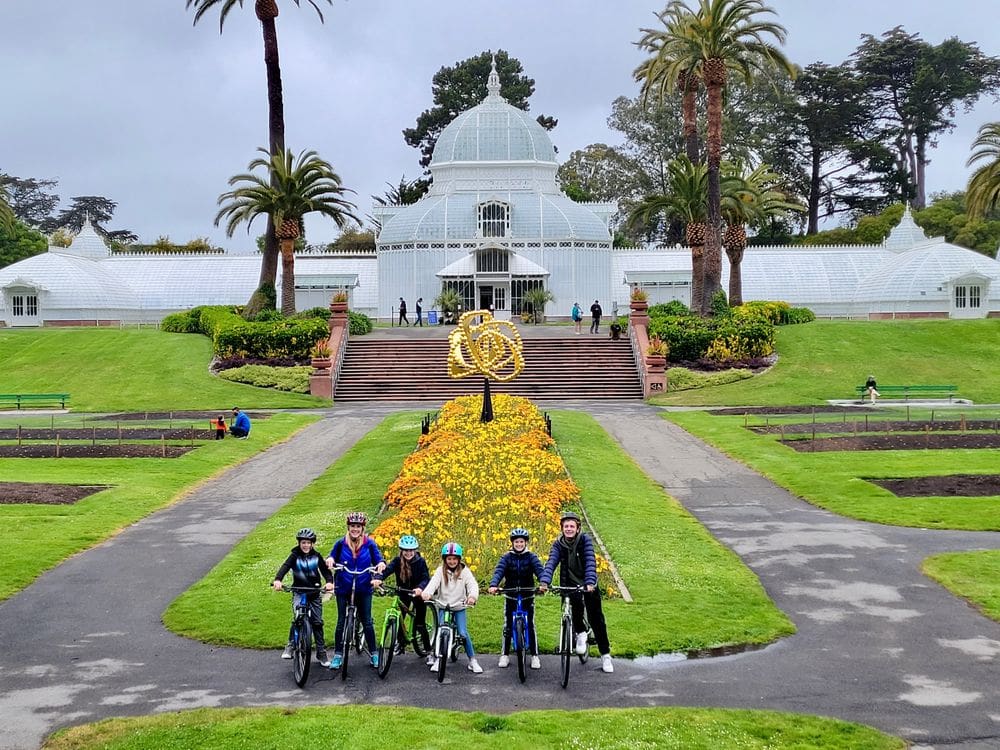 A family of six sits on their bikes while on a tour of Golden Gate Park, one of the best things to do in San Francisco with kids.