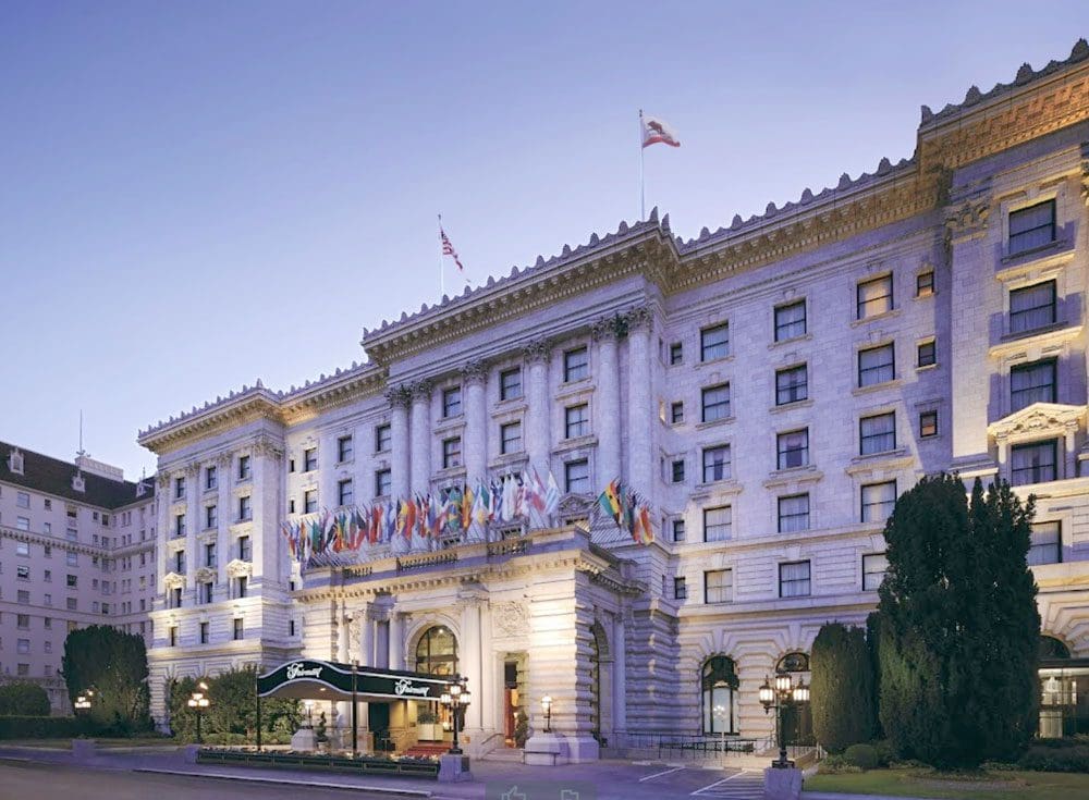 The entrance to the Hotel Fairmont San Francisco, with international flags over the stone entrance.