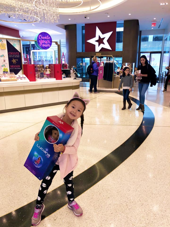 A young girl stands with her prized American doll within the store.