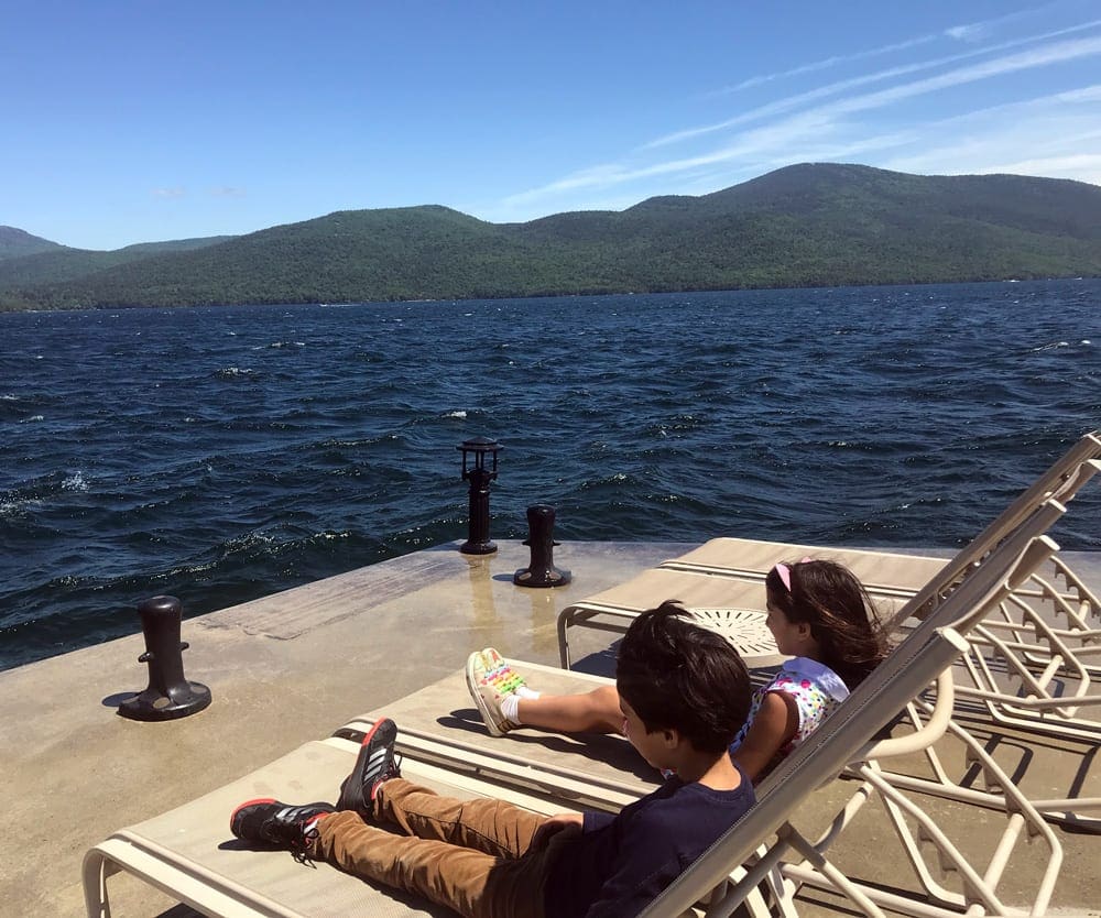 Two kids sit on loungers near the water at the Sagamore Resort.