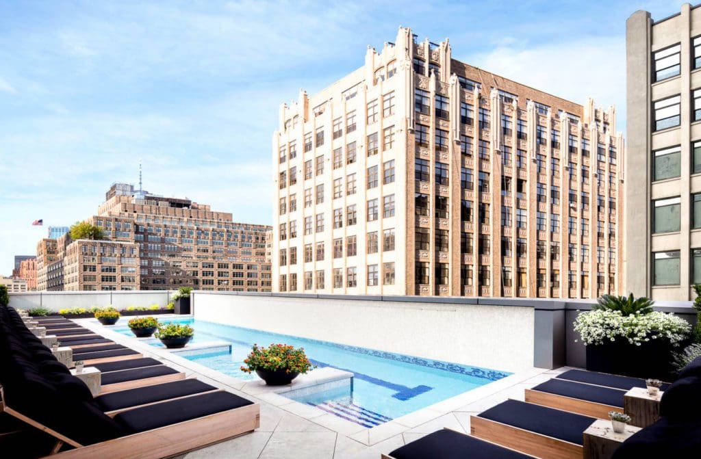 The rooftop pool at the The Dominick Hotel, featuring poolside loungers and views of nearby historic buildings.