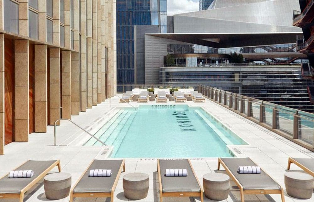 A view of the outdoor pool, with nearby loungers, at the The Equinox Hotel New York.