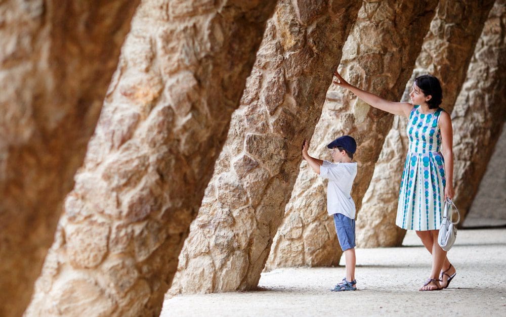 A mom and her young son touch a large stone wall in Barcelona.