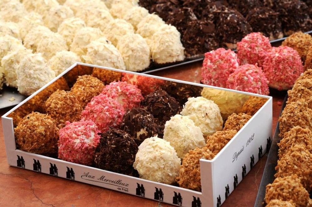 Several bon bons rest in a box waiting to be ordered at Aux Merveilleux de Fred, one of the best dessert destinations in Paris for families.