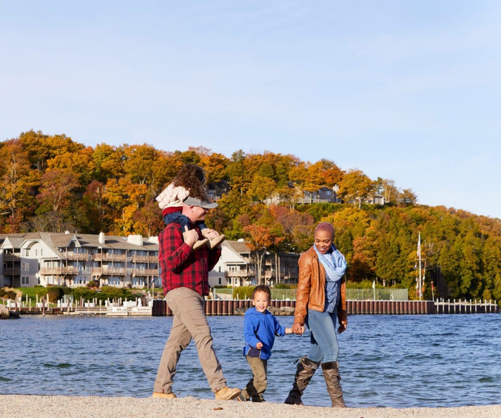 A family of four walks together on a crisp fall day along the water near Sister Bay in Door County, one of the best places to visit in Wisconsin for families.