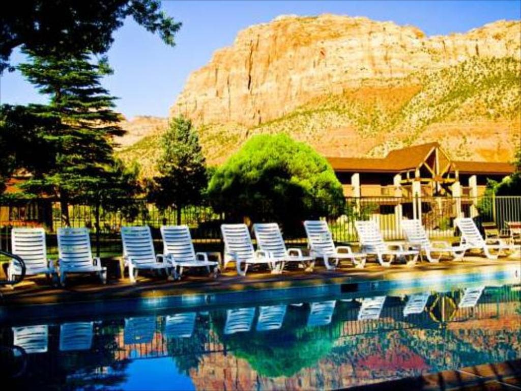The pool at the Driftwood Lodge Springdale, reflecting the view of the large desert rock formations in the distance. This is a great options if you're wondering where to stay near Zion National Park with kids!