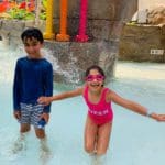 Two kids in swim suits enjoy a splash at the indoor waterpark at Kartrite.