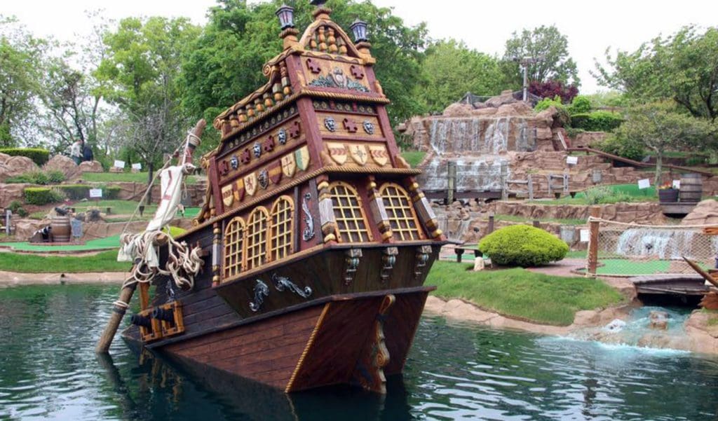 A large pirate ship pokes out of the water on a minigolf course at the Pirate’s Cove Adventure Golf in Cape Cod.