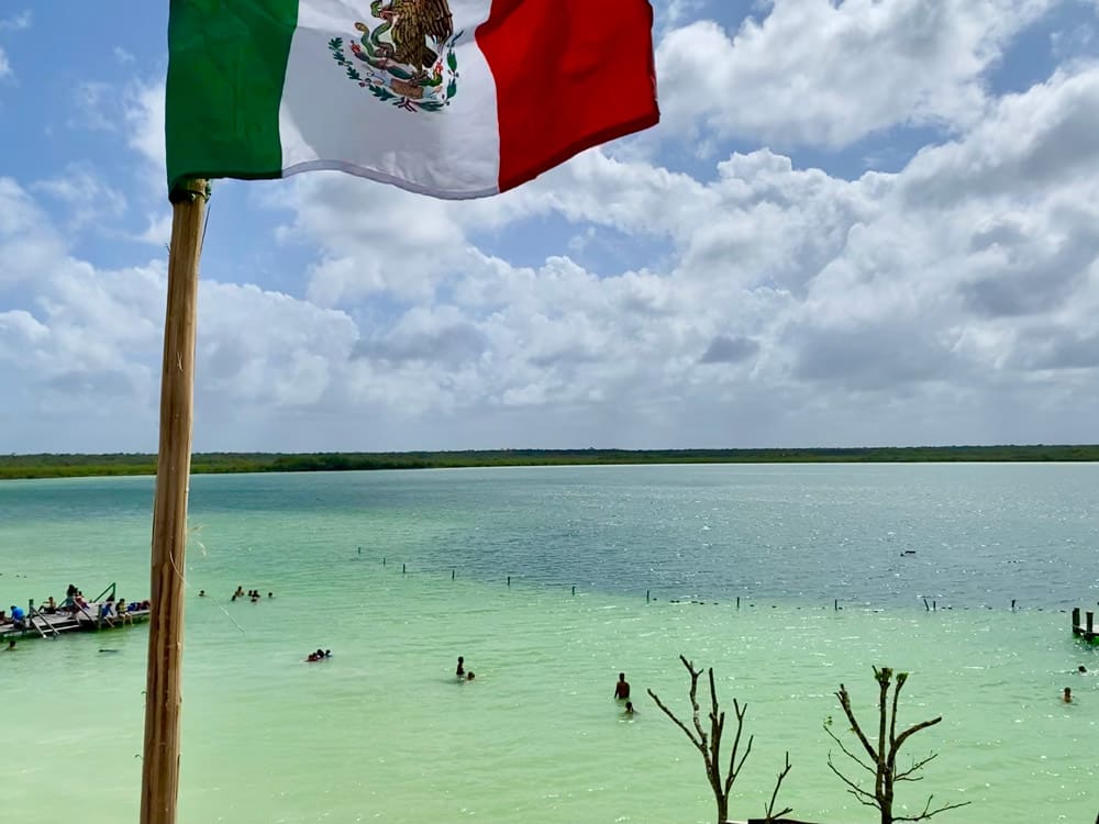 A Mexican flag flies high above a shoreline near Laguna Kaan Luum.