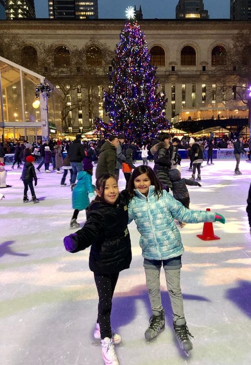 Two young girls pose together on skates, while they enjoy an evening of skating at the ice rink at Bryant Park.
