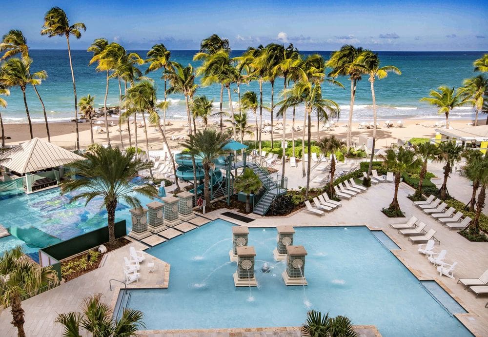 An aerial view of the pool area, large slide, and pool deck at the San Juan Marriott Resort & Stellaris Casino, one of the best Marriott Resorts in the Caribbean for families.