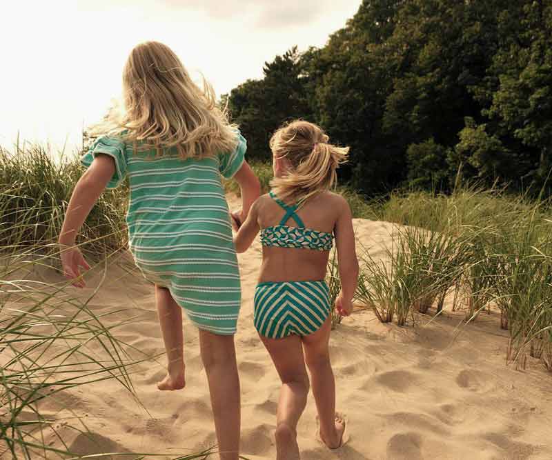 Two young girls run hand-in-hand along the sand at Oval Beach in Saugatuck.