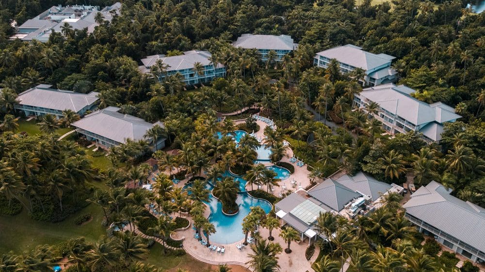 Aerial view of the outdoor pool at the The St. Regis Bahia Beach Resort, Puerto Rico, surrounded by the hotel's various buildings.
