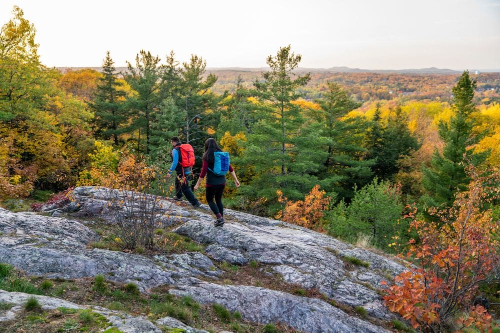 Two hikers wearing backpacks enjoy a fall hike in Marquette, , one of the best places to visit in Michigan’s Upper Peninsula with kids.