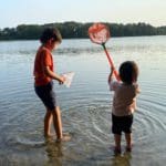 Two boys playing in the water in Cape Cod with small minnow nets.