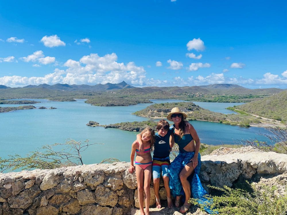 A mom and two kids pose together as they enjoy a beautiful view of Curacao.
