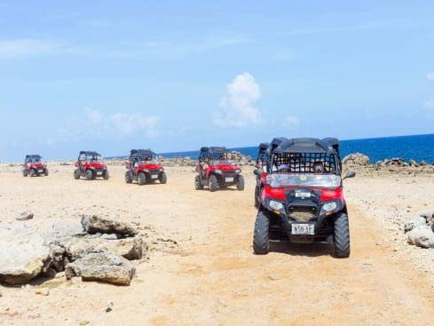 Several ATVs ride in a line as they traverse across Curacao.