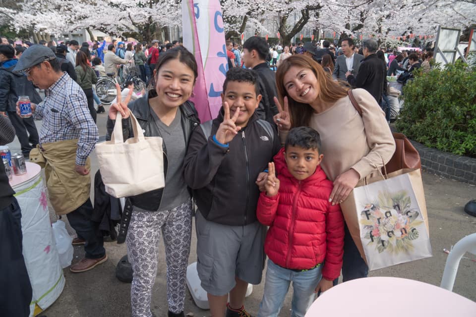 Two woman stand with two kids while enjoying the Sakura Picnic in Ueno Park in Tokyo.
