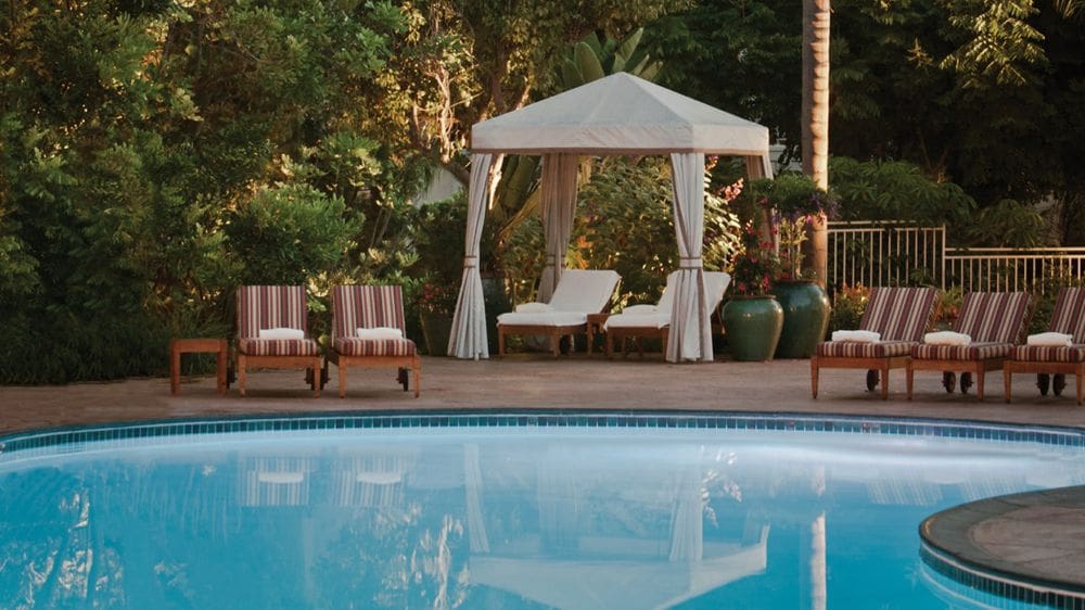 Across a pool sits a cabana and several poolside loungers at Four Seasons Residence Club Aviara, North San Diego.
