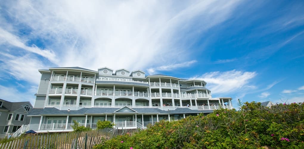 The exterior to the Madison Beach Hotel, Curio Collection By Hilton, on a sunny day, one of the best hotels in Connecticut for families.