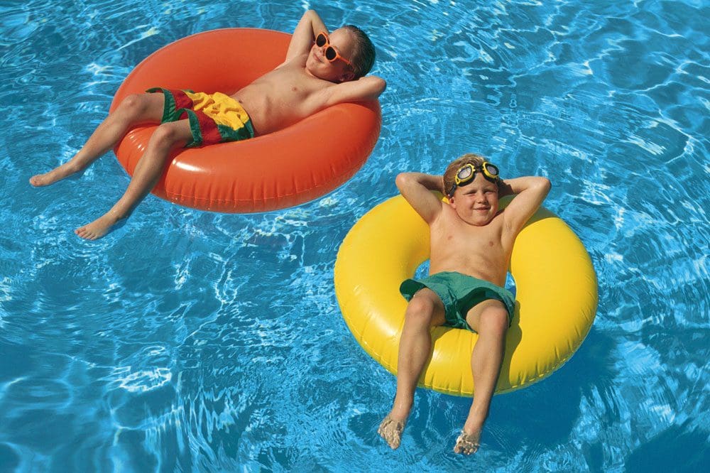 Two boys enjoy the pool a the Manchester Grand Hyatt San Diego, one floating in an orange tube, while the other floats in a yellow tube.