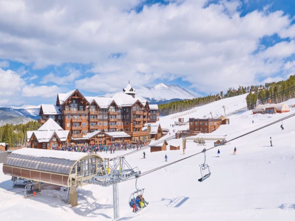 A view of One Ski Hill Place, across the snowy mountain, featuring their resort grounds and chairlift, one of the best best ski in ski out resorts in Colorado.