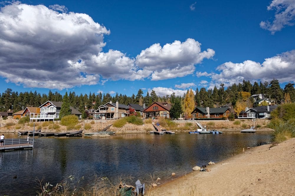 Several lake houses on Big Bear Lake in California are surrounded by fall colors of green and yellow.