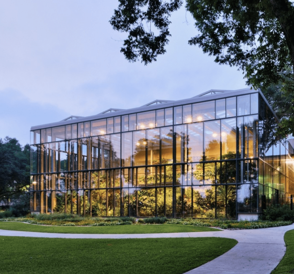 The lit-up glass exterior of the Texas Discovery Gardens at dusk.