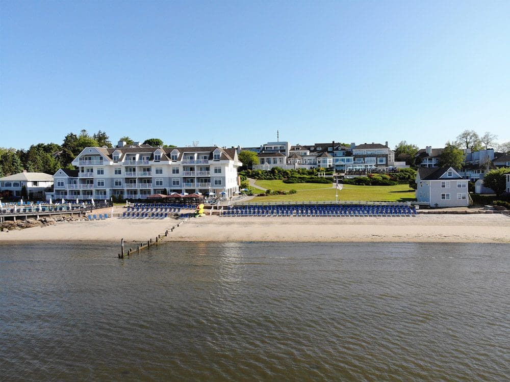 A view of the Water’s Edge Resort and Spa from the water, featuring a long shoreline on a sunny day, one of the best hotels in Connecticut for families.