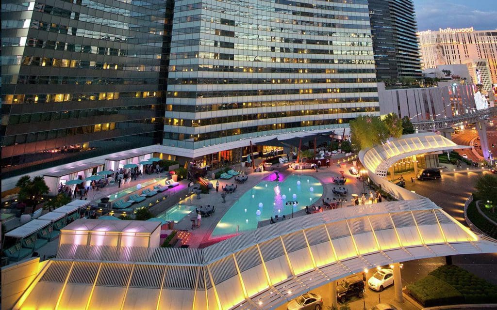 An aerial view of the Vdara Hotel and Spa, featuring its hotel building and pool area at night, one of the best hotels in Las Vegas for families.