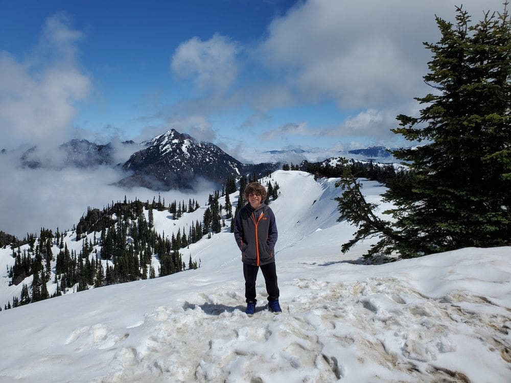 A young boy stands in the snow while exploring Hurricane Ridge, one of the best hikes near Seattle for families.