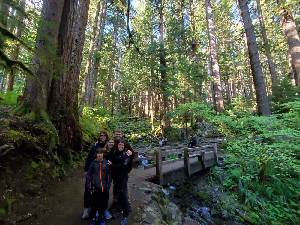 A family of five stands together while hiking along Sol Duc Falls in Washington.