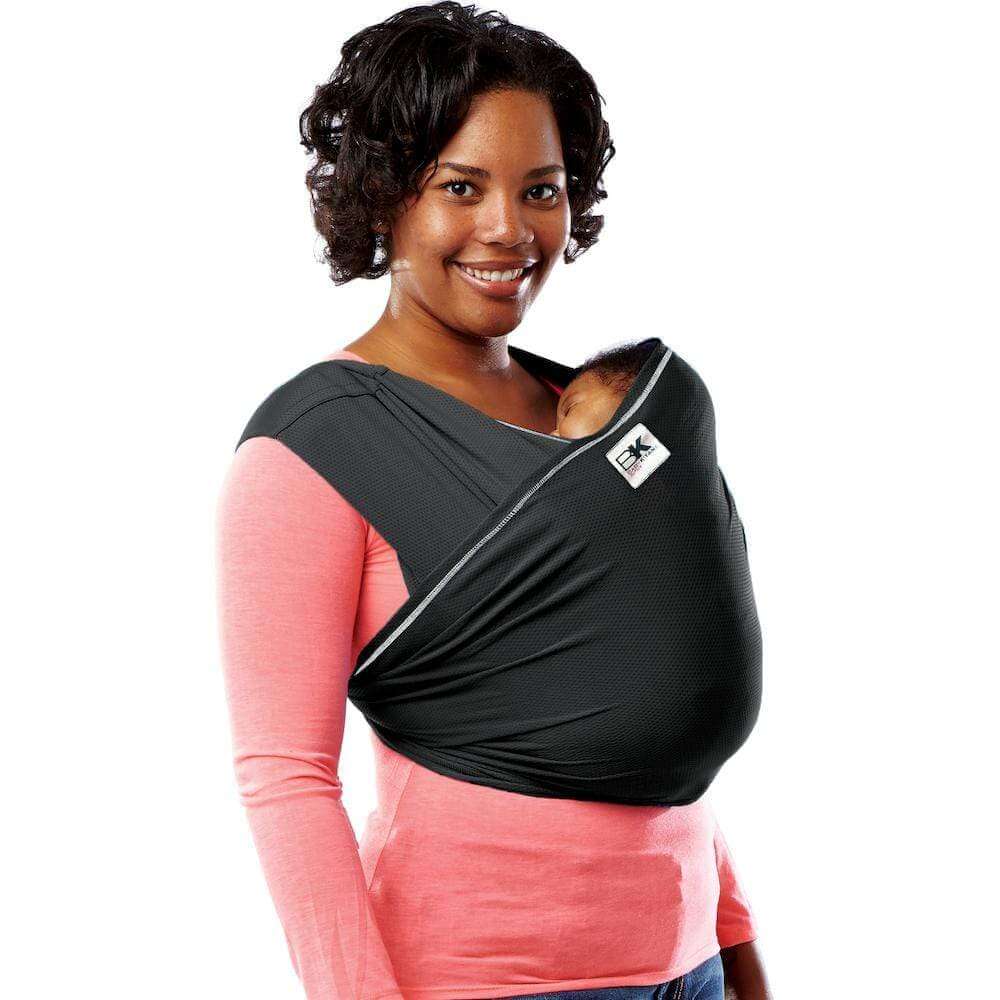 An African-American mom holds her child in a front carrier by Baby K'tan Baby Carrier, one of the best baby carriers for travel.