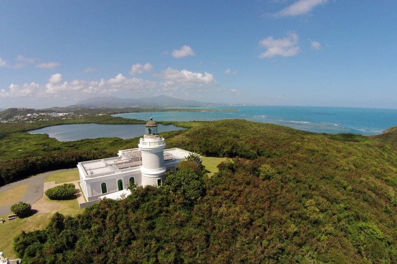 An aerial view of the white building for Cabezas de San Juan Nature Reserve, surrounded by lush greenery, with the ocean in the distance, one of the best things to do in Puerto Rico with kids.