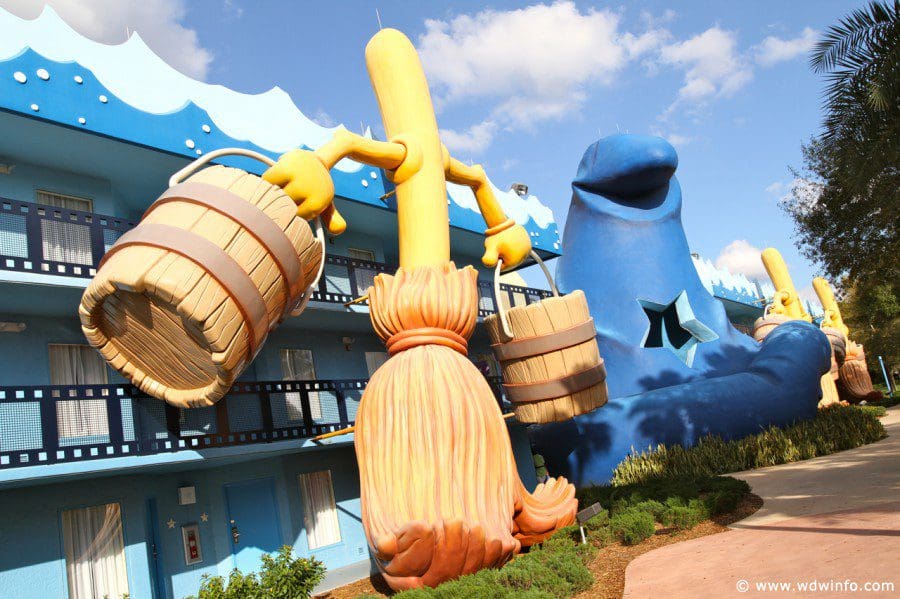 A large statue from a Disney film, featuring a walking broom and sorcerer's hat, shown on the side of one of the buildings at Disney’s All-Star Movies Resort.