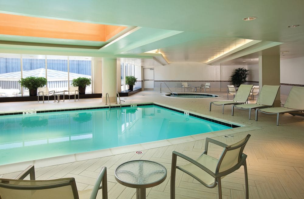 The indoor pool at the The Embassy Suites by Hilton Washington Chevy Chase Pavilion, with poolside chairs flanking the pool.
