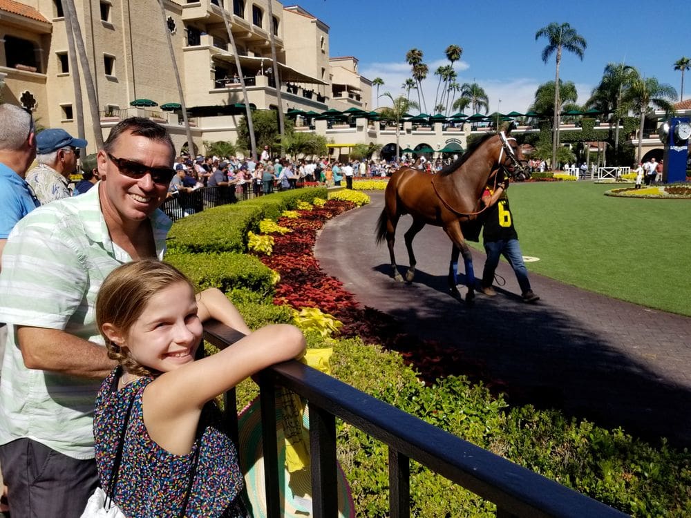 A dad and his young daughter smile while enjoying a race at Del Mar Race Track.