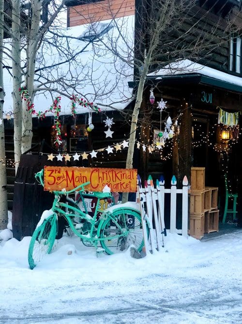 A bike sits in the snow with a sign reading "3rd and Main Christkindl Market" in Frisco.