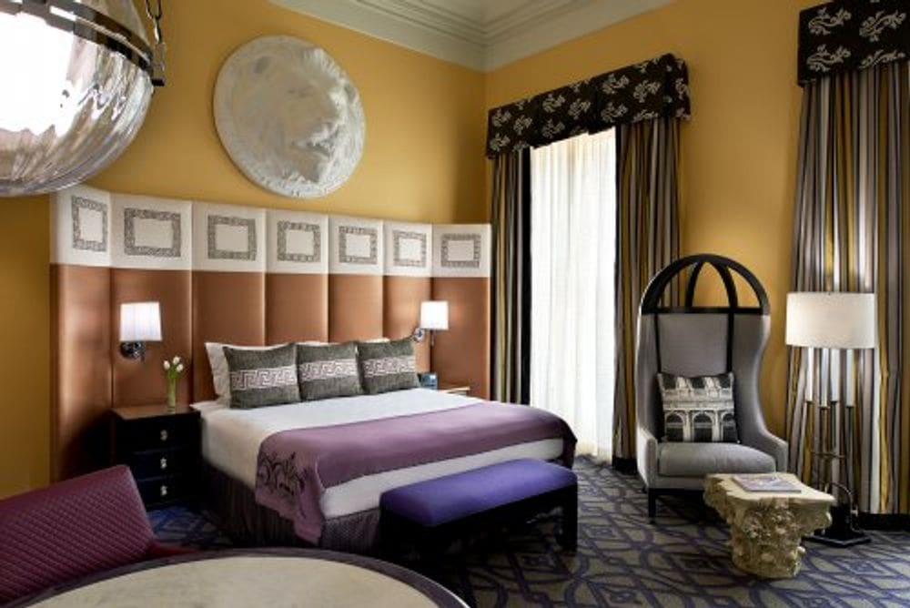 Inside one of the guest rooms at the Photo Courtesy: Kimpton Hotel Monaco Washington DC, featuring gold and purple accents.