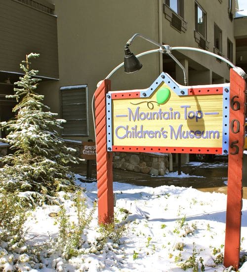 A sign reads "Mountain Top Children's Museum" with snow around it.
