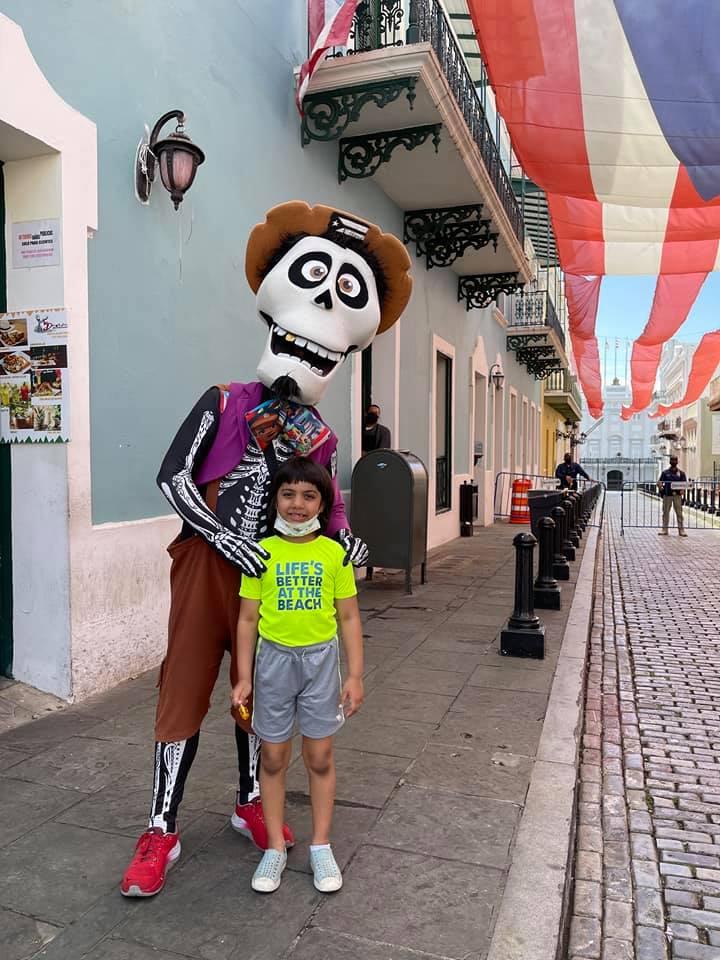 A young boy stands with a street performer dressed like a character from Disney's Coco.