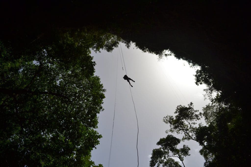 A man descends on a rope into a river on a tour with Tamana River Adventures.