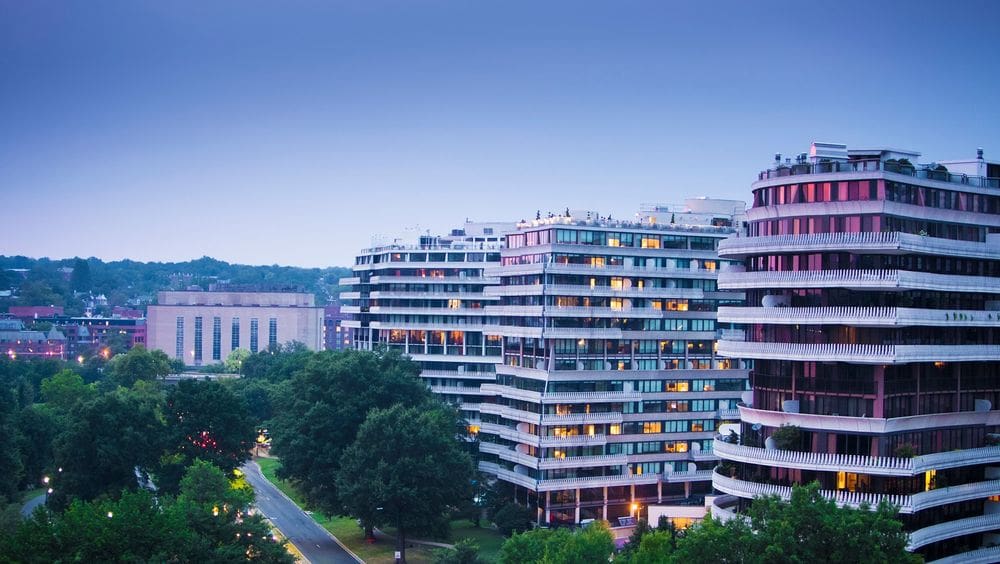 The exterior of The Watergate Hotel at dusk, featuring hues of blue and purple.