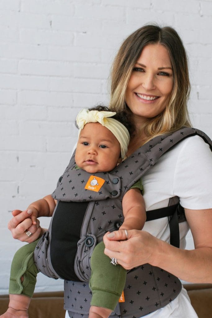 Close up of a woman holding her child in a front carrier by Tula Coast Explore Mesh Baby Carrier.